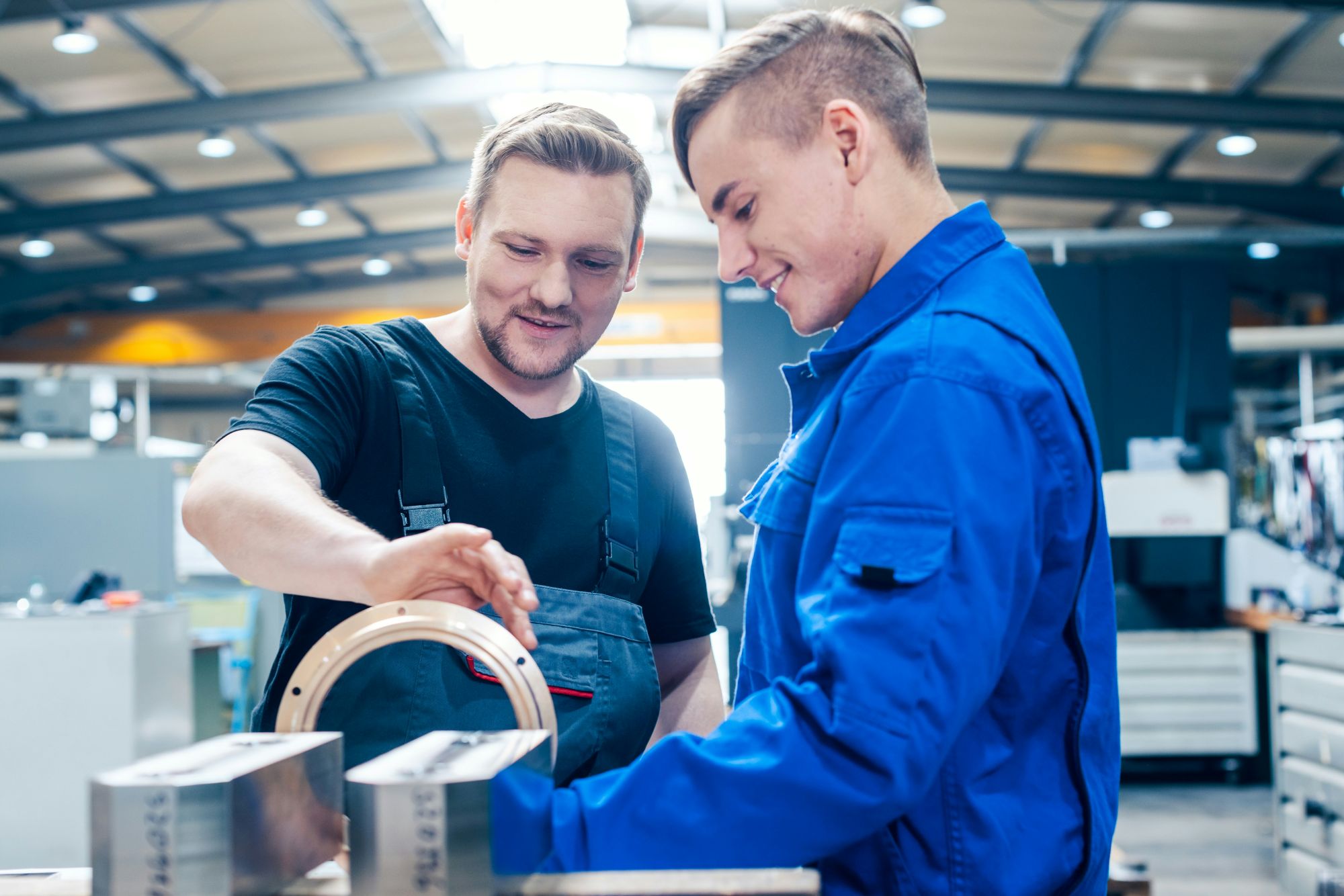 Two people in a factory setting working together on a machine