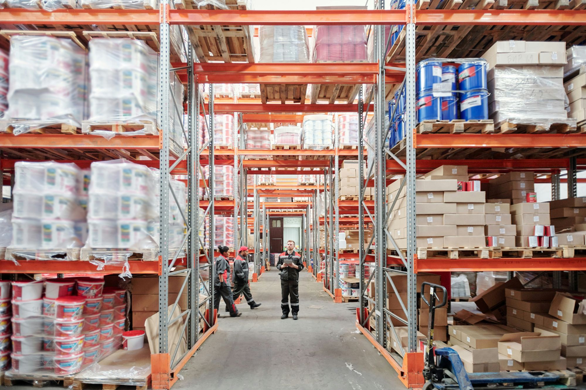 Three workers in a warehouse with full stakced shelves